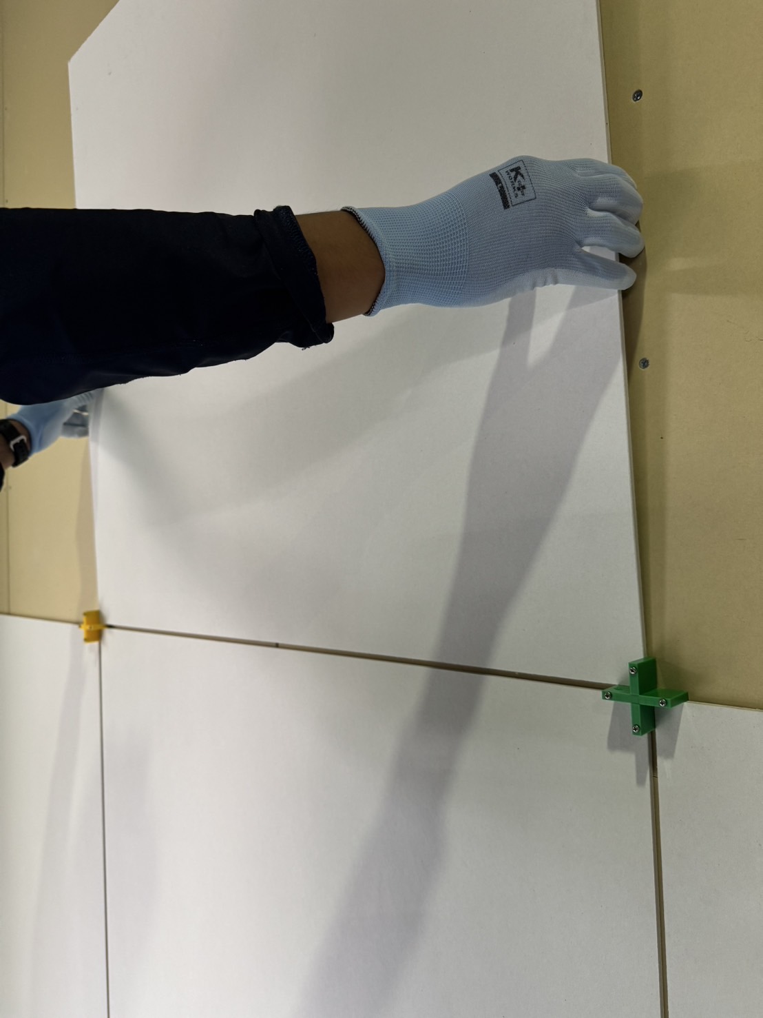 壁面に化粧板を一人で押さえながら施工している様子。メジスカットが板を固定しているため両手が使える。